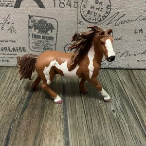 A brown and white paint horse stallion with pink nail polish hooves